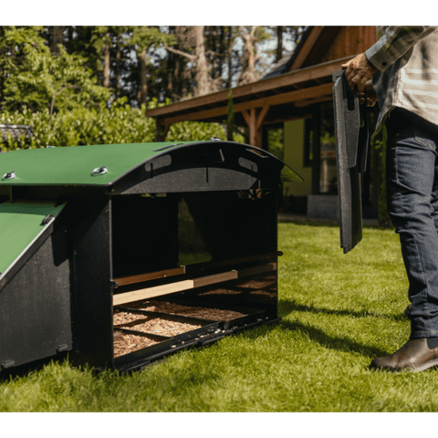 Nestera kunststof kippenhok groot sfeerfoto, op het gras in een achtertuin met verwijderde achterzijde en iemand die de achterzijde vasthoudt.