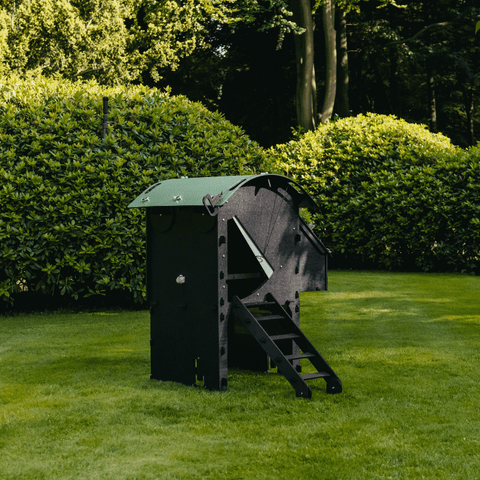 Sfeerfoto Nestera kunststof kippenhok op wielen, schuin vooraanzicht in een achtertuin op het gras.
