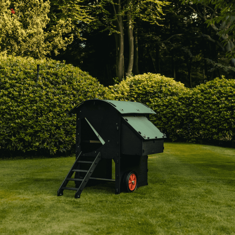 Sfeerfoto Nestera kunststof kippenhok op wielen, schuin vooraanzicht in een achtertuin op het gras.